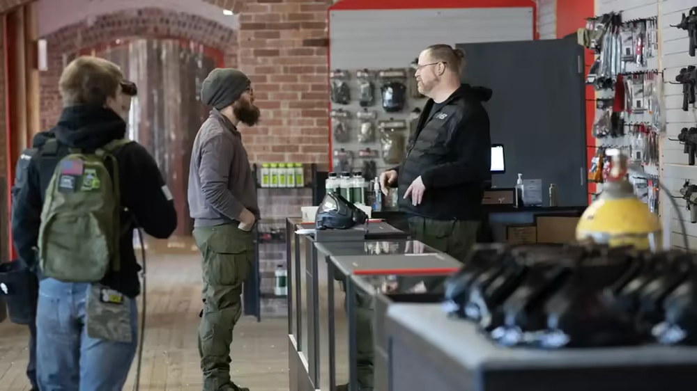 Customers talking to staff in the Advanced Action Sports shop area with retail displays and gear for sale