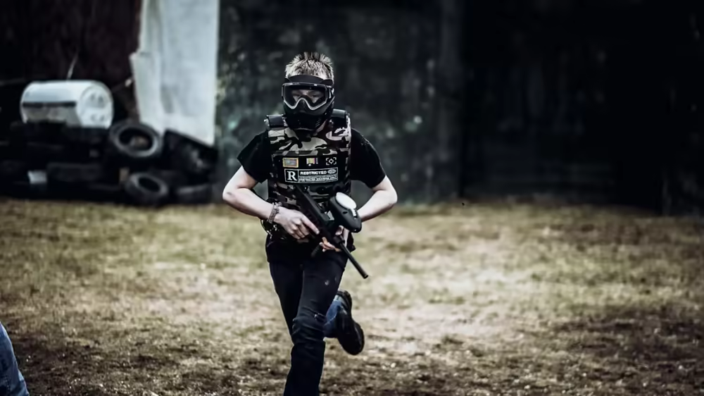 Young paintball player running across the field in dynamic action shot