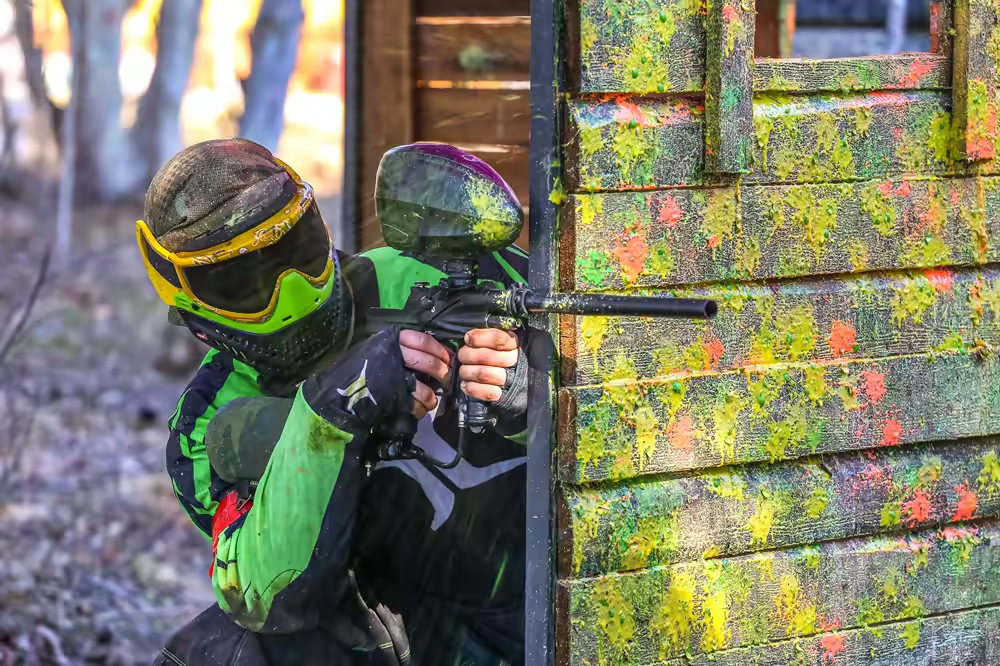 Bright colorful paintball action with paint splattering around a barricade
